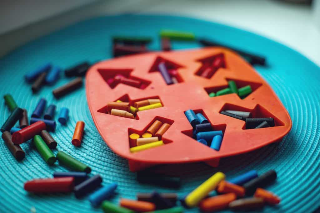 Cut up pieces of crayons put into baking tray arrow shaped templates to be melted and repurposed 