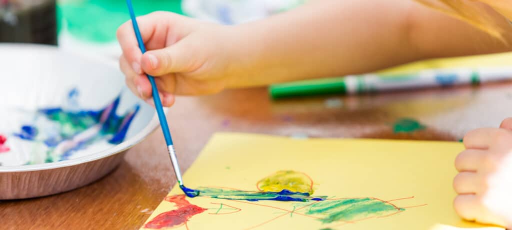 young girl doing arts and craft with paint and more